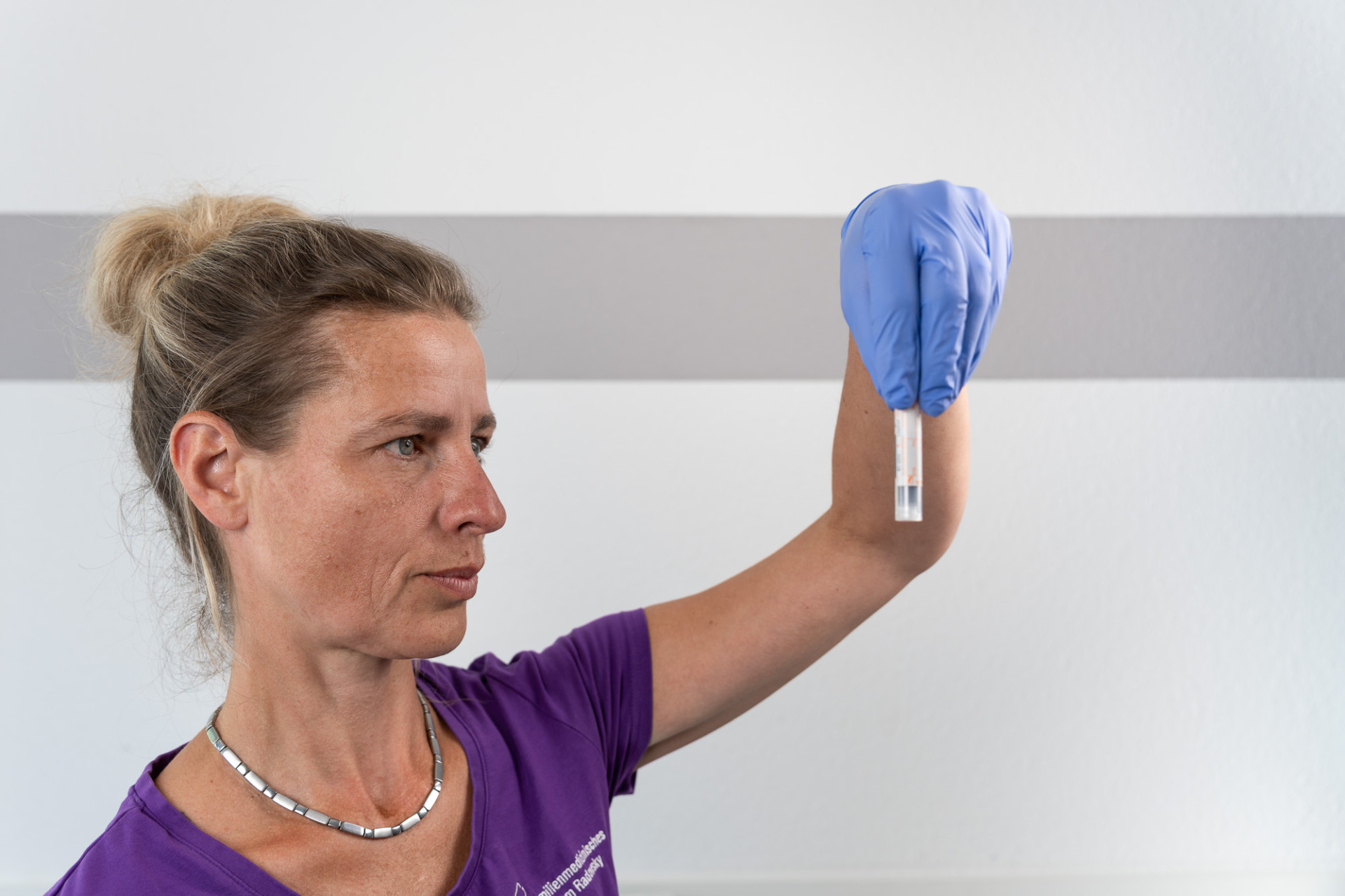 Mitarbeiterin FMZ Radowsky schaut auf ein Röhrchen mit medizinischer Probe